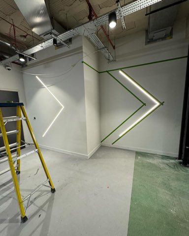 Car park wall being prepared and painted with an illuminated chevron graphic during works