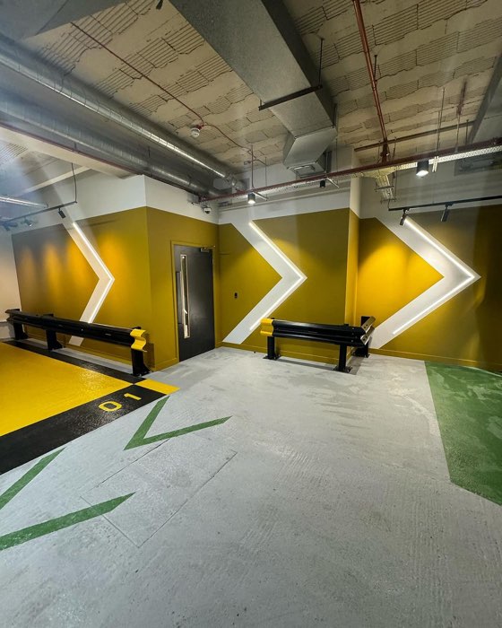 Multi-storey car park bay painted with yellow and black floor markings and an illuminated chevron feature wall