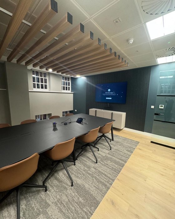 Corporate boardroom with dark feature wall, wood slat ceiling detail and conference table, freshly decorated